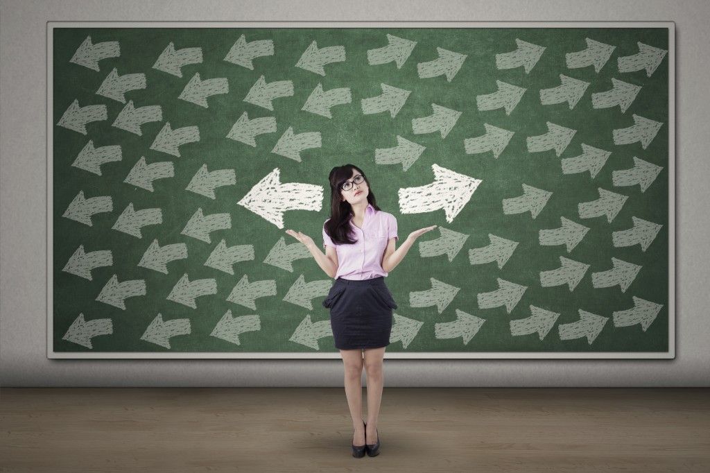 Confused business woman with arrows on blackboard